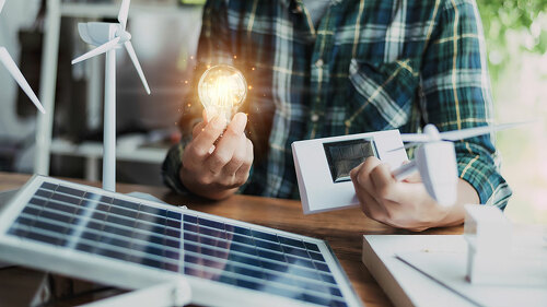 Close-up at a light bulb, An engineer sits holding a light bulb