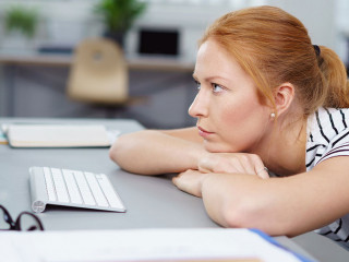 frau im büro schaut genervt auf ihren pc