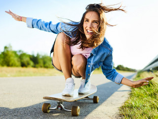 Cheerful young woman riding longboard in countryside setting