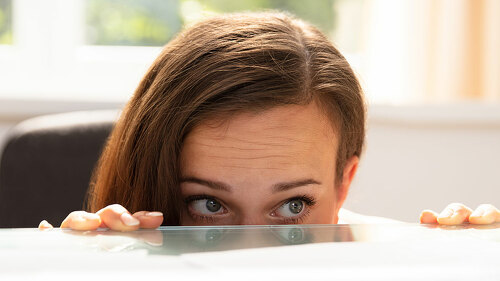Businesswoman Peeking Behind The Desk