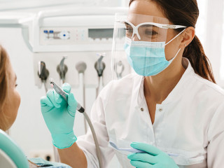 European mid dentist woman in face mask working in dental clinic