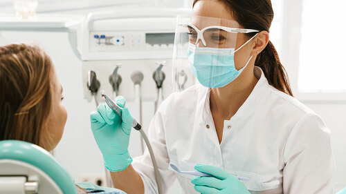 European mid dentist woman in face mask working in dental clinic
