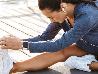 Fitness woman make stretching exercises at the beach outdoors listening music with earphones.
