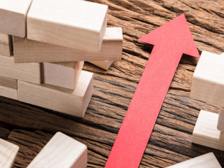 Red Paper Arrow Amidst Blocks On Wooden Table