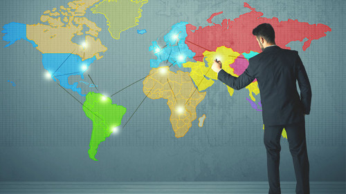 mann-im-anzug-vor-weltkarte-bunt-102643078-FO-ra2_studio