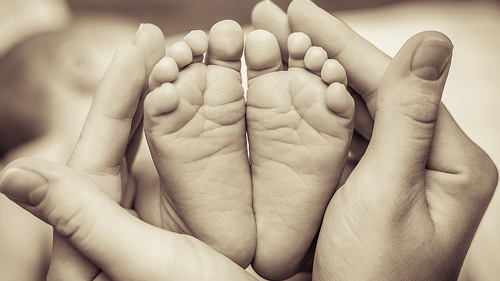 baby-fuesse-in-frauen-haenden-69112978-FO-honcharr