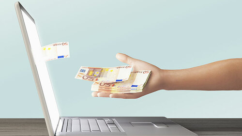 Fuenfziger-aus-Laptop-auf-Hand-101908439-FO-ALDECAstudio