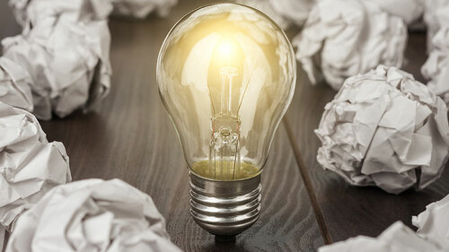 Gluehbirne-zwischen-zerknuelltem-Papier-92379231-FO-Ruslan-Grumble