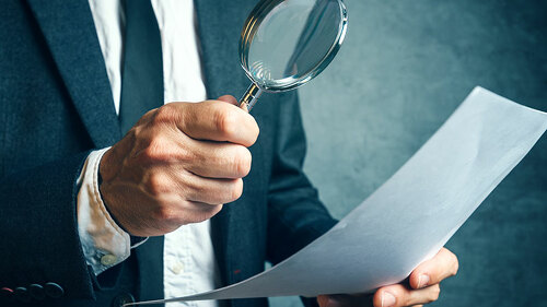 mann-untersucht-blatt-papier-mit-lupe-111306547-FO-Bits-and-Splits