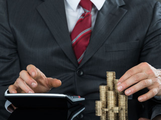 mann-stapelt-muenzen-taschenrechner-106256671-fo-andrey-popov