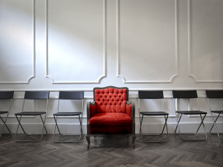 roter-sessel-zwischen-stuehlen-121400541-olly