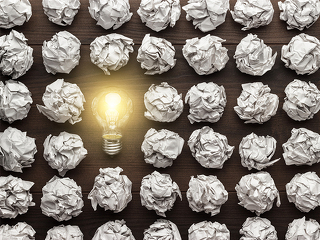 Gluehbirne-zwischen-zerknuelltem-Papier-80363721-FO-Ruslan-Grumble