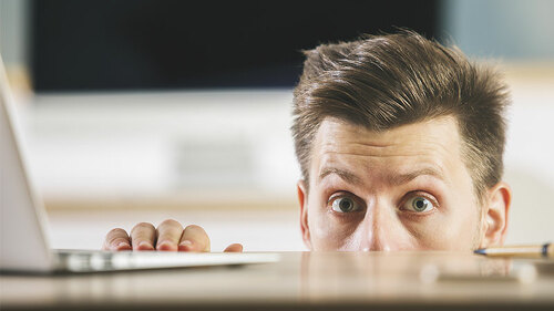 Anzugtraeger-versteckt-sich-unter-Tisch-162759425-FO-peshkova