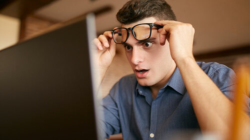 Mann-Brille-Laptop-ueberrascht-191749520-FO-artiemedvedev