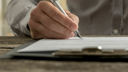 Anzugtraeger-unterschreibt-Dokument-151145415-FO-Gajus