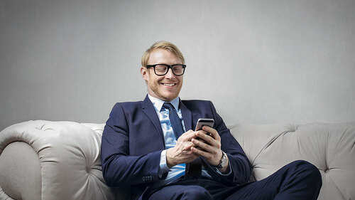 mann-lachend-auf-couch-handy-140714203-FO-olly