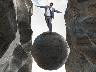 Anzugtraeger-balanciert-auf-Fels-in-Schlucht-171963772-FO-Elnur