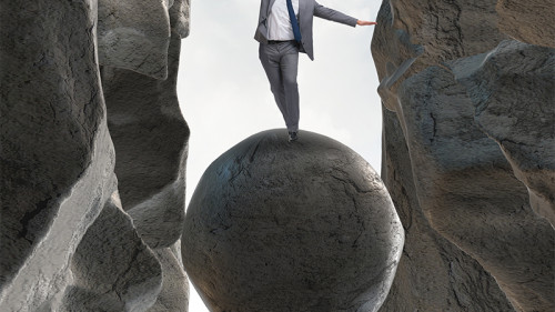 Anzugtraeger-balanciert-auf-Fels-in-Schlucht-171963772-FO-Elnur