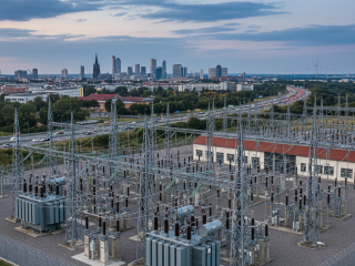 Energieinfrastruktur im urbanen Raum: Umspannwerk mit Hochspannungsanlagen vor der Skyline einer deutschen Großstadt.
