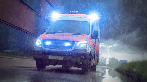 Ein Rettungswagen im Einsatz bei starkem Regen – Symbolbild für die strukturellen Herausforderungen der Notfallversorgung.
