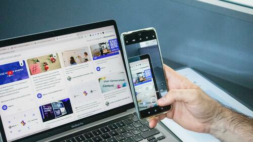 Close-up of a smartphone capturing a laptop screen, representing technology integration.